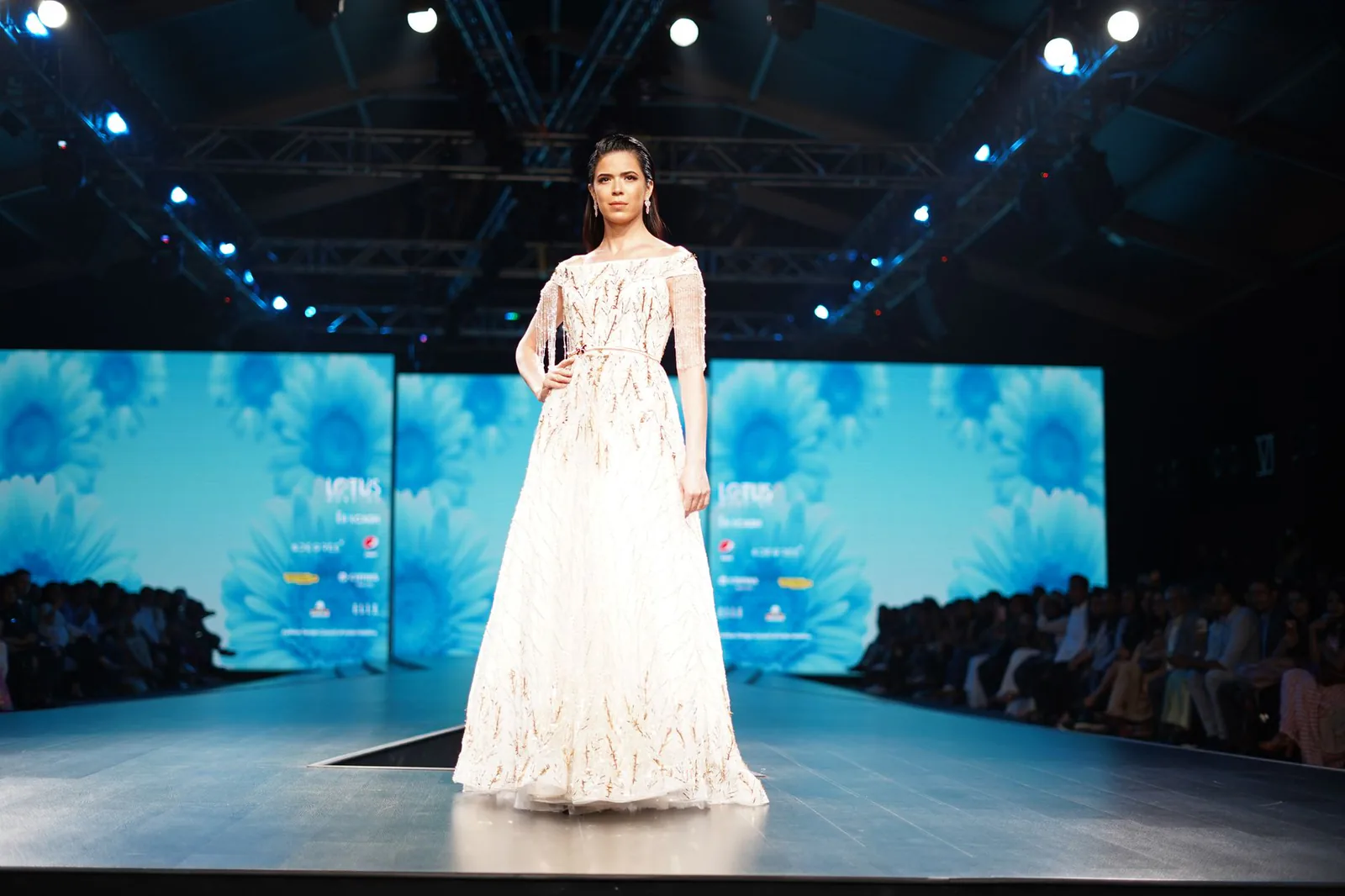 Model showcasing white dress on fashion runway